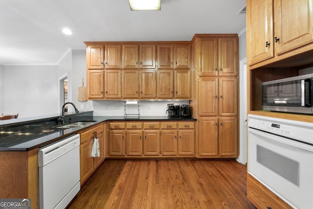 kitchen featuring white appliances, sink, dark stone countertops, ornamental molding, and dark hardwood / wood-style flooring