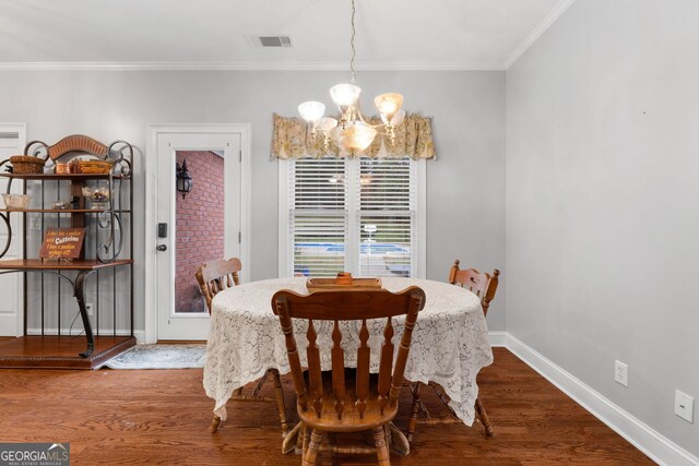 dining area with dark hardwood / wood-style flooring, ornamental molding, and a notable chandelier