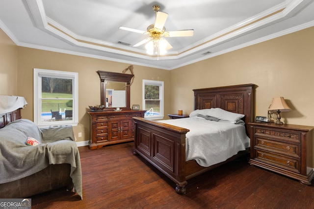 bedroom with ceiling fan, dark hardwood / wood-style floors, and a tray ceiling