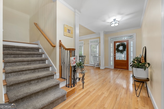 entrance foyer with hardwood / wood-style flooring, ornate columns, and crown molding