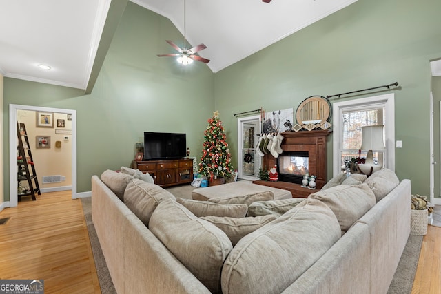 living room featuring ceiling fan, light hardwood / wood-style floors, ornamental molding, and high vaulted ceiling