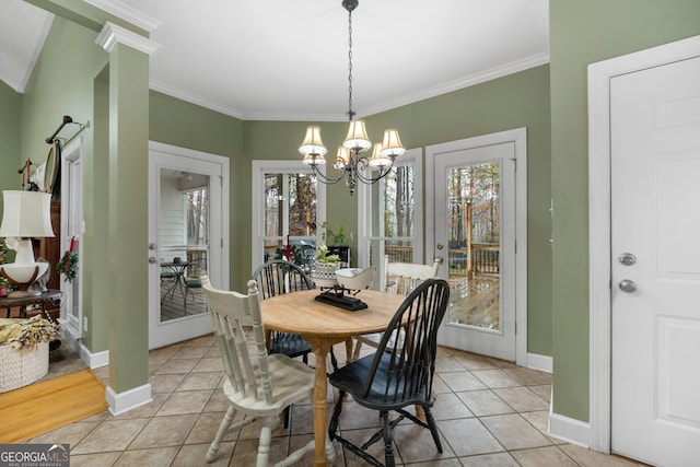 tiled dining area with a healthy amount of sunlight, crown molding, and a chandelier