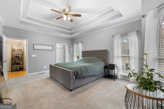 carpeted bedroom with a raised ceiling, ceiling fan, and ornamental molding