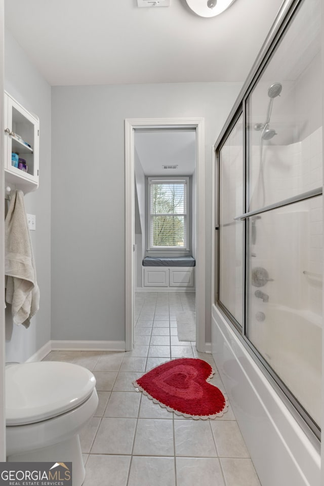 bathroom featuring tile patterned flooring, enclosed tub / shower combo, and toilet