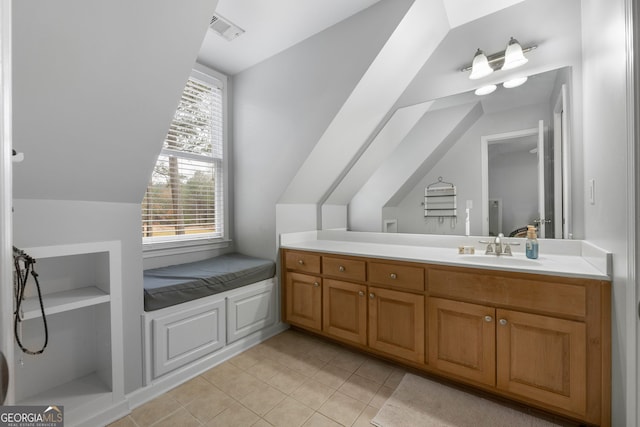 bathroom with tile patterned flooring, vanity, and vaulted ceiling