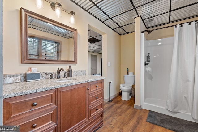 bathroom featuring wood-type flooring, vanity, toilet, and walk in shower