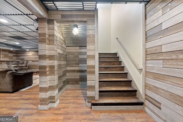 stairs with hardwood / wood-style flooring and wooden walls