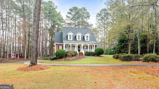 cape cod home with covered porch and a front yard