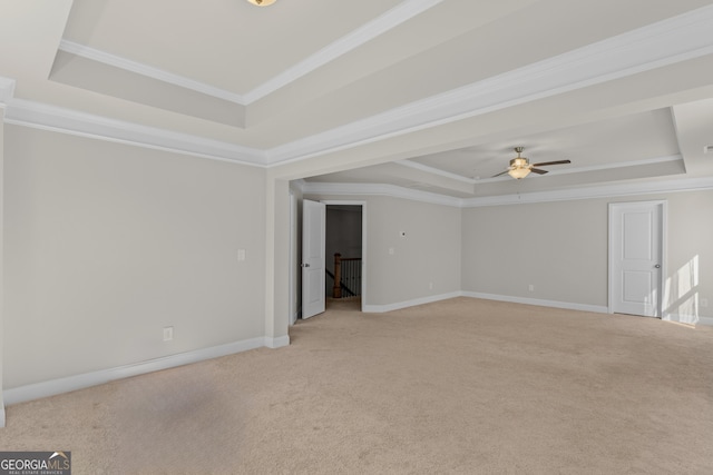 carpeted spare room with a raised ceiling, crown molding, and ceiling fan