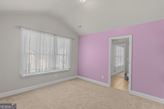 unfurnished bedroom with light colored carpet and vaulted ceiling