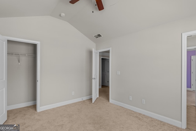 unfurnished bedroom with light carpet, lofted ceiling, a closet, and ceiling fan