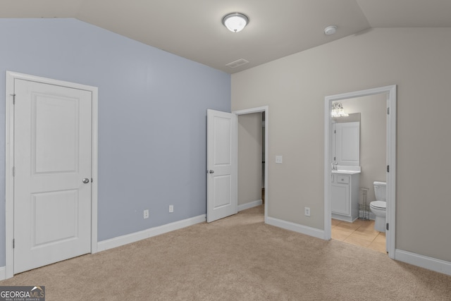 unfurnished bedroom with light carpet, lofted ceiling, and ensuite bathroom