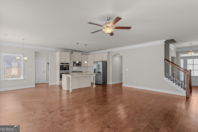 unfurnished living room with ceiling fan with notable chandelier, ornamental molding, and hardwood / wood-style flooring