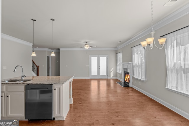 kitchen with pendant lighting, white cabinetry, dishwasher, sink, and light stone counters