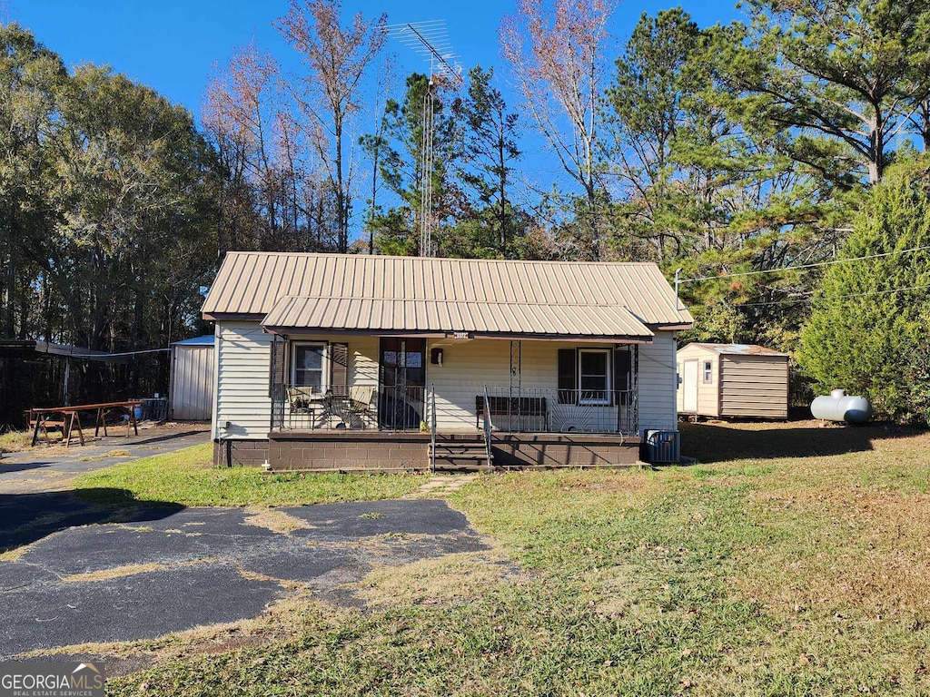 view of front facade featuring a porch, a storage unit, and a front lawn