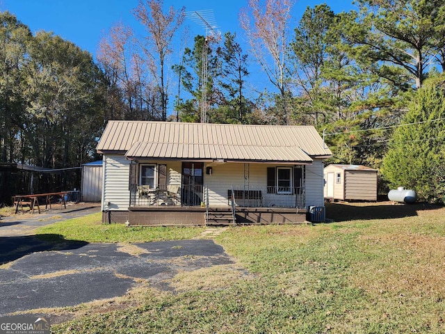 view of front facade featuring a porch, a storage unit, and a front lawn