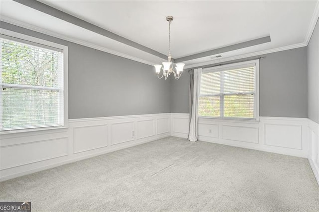 empty room with light colored carpet, an inviting chandelier, a wealth of natural light, and ornamental molding