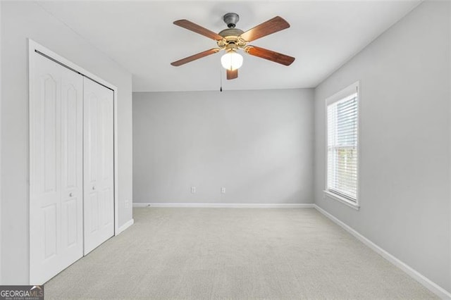 unfurnished bedroom with ceiling fan, a closet, and light carpet