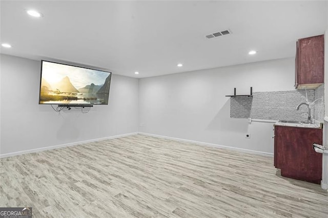 basement with light wood-type flooring and sink