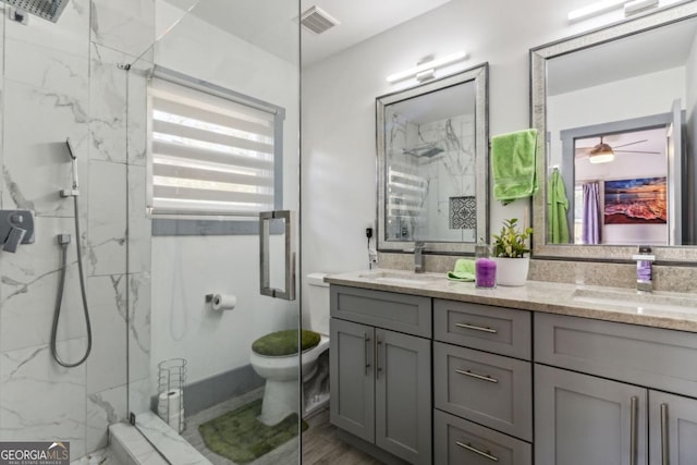 bathroom with tiled shower, vanity, hardwood / wood-style flooring, and toilet