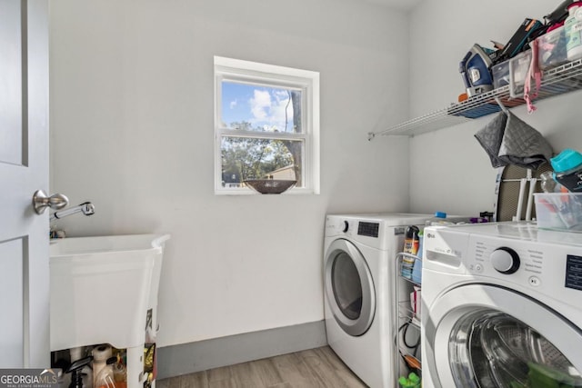 laundry room featuring washer and clothes dryer, light hardwood / wood-style floors, and sink