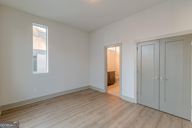 unfurnished bedroom with connected bathroom, light hardwood / wood-style floors, and a closet