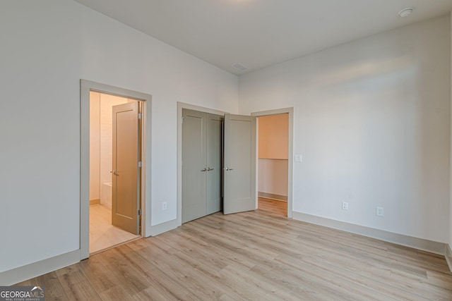 unfurnished bedroom with connected bathroom and light hardwood / wood-style flooring