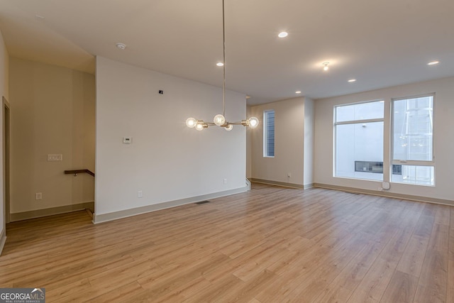 unfurnished room with a notable chandelier and light hardwood / wood-style flooring