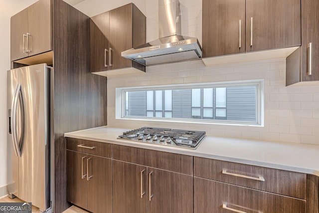 kitchen featuring wall chimney range hood, stainless steel appliances, and tasteful backsplash