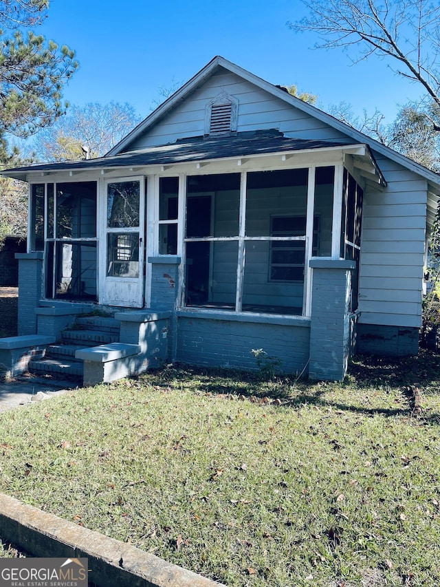 view of front of house with a sunroom and a front yard