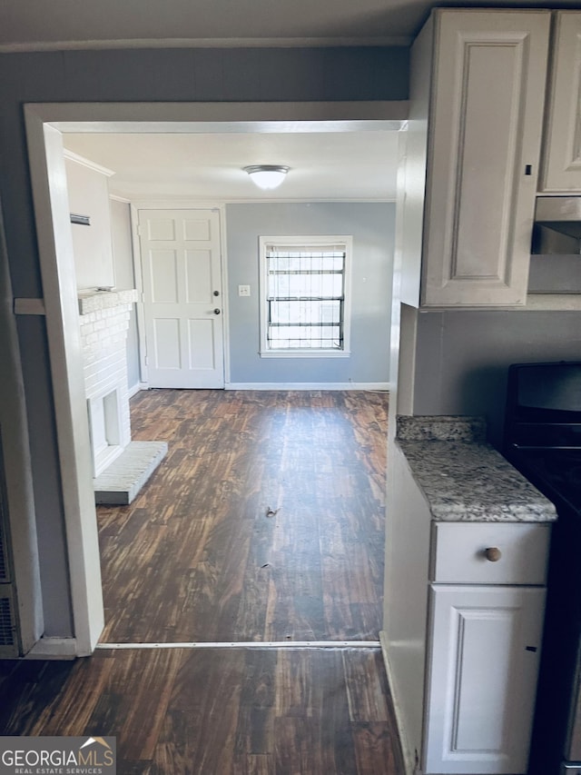 kitchen featuring light stone countertops, stove, dark hardwood / wood-style floors, and a brick fireplace