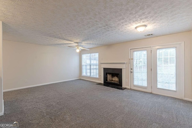 unfurnished living room featuring a textured ceiling, carpet floors, and ceiling fan