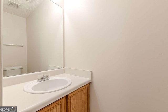 bathroom featuring vanity, a textured ceiling, and toilet