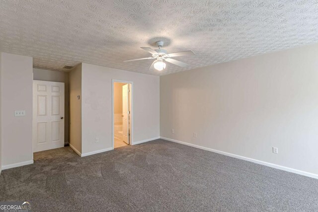 unfurnished bedroom with a textured ceiling, carpet floors, ensuite bath, and ceiling fan