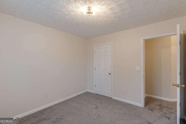 empty room featuring light carpet and a textured ceiling