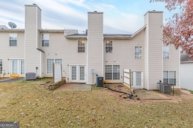 rear view of house featuring central air condition unit, a patio area, and a lawn