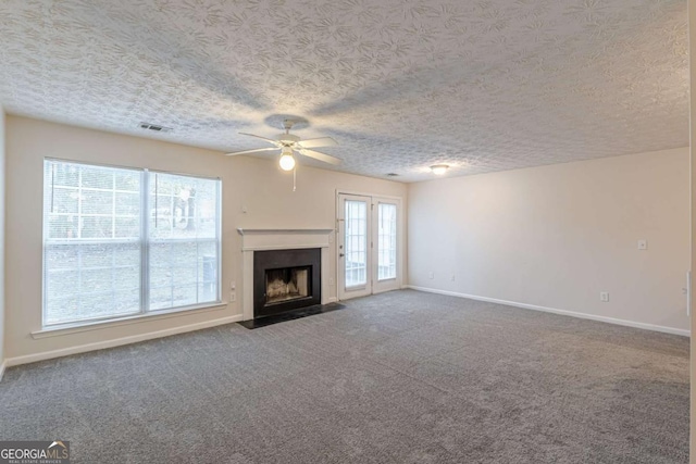 unfurnished living room featuring carpet, a textured ceiling, and ceiling fan