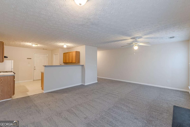 unfurnished living room with light carpet, ceiling fan, and a textured ceiling