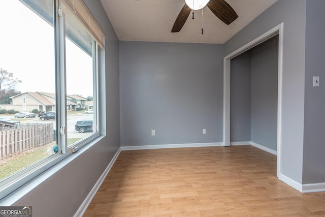 empty room with ceiling fan, plenty of natural light, and light hardwood / wood-style floors