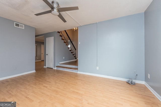 unfurnished room with a textured ceiling, light hardwood / wood-style flooring, and ceiling fan with notable chandelier