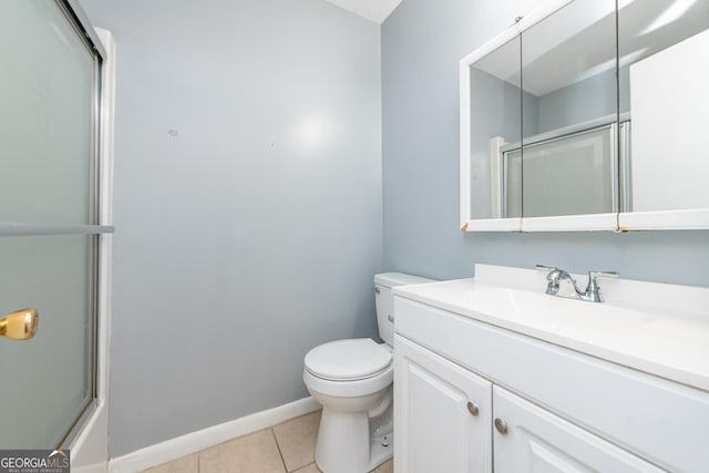 bathroom featuring tile patterned floors, vanity, a shower with shower door, and toilet