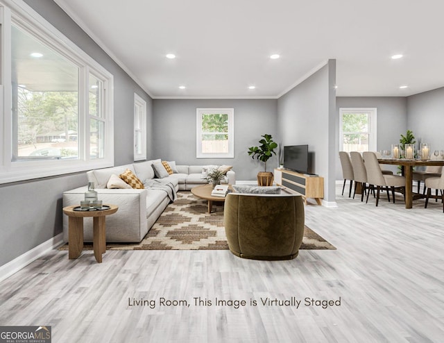 living room featuring crown molding, a healthy amount of sunlight, and light wood-type flooring