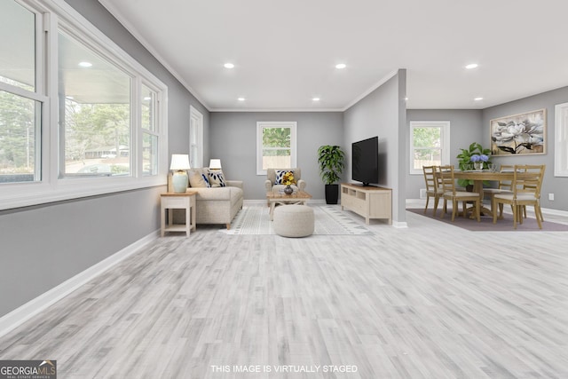 living room featuring crown molding, a healthy amount of sunlight, and light hardwood / wood-style floors