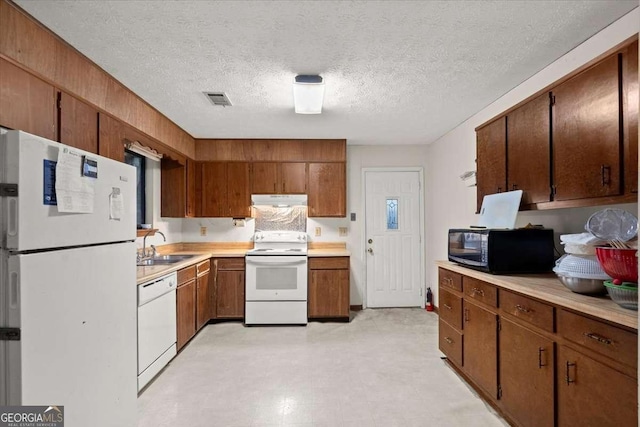 kitchen featuring a textured ceiling, sink, and white appliances