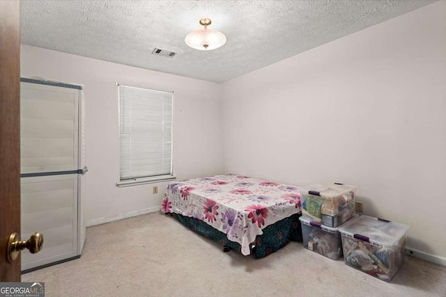 bedroom featuring light carpet and a textured ceiling