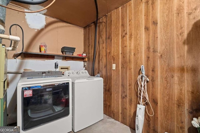 laundry room featuring separate washer and dryer and wooden walls