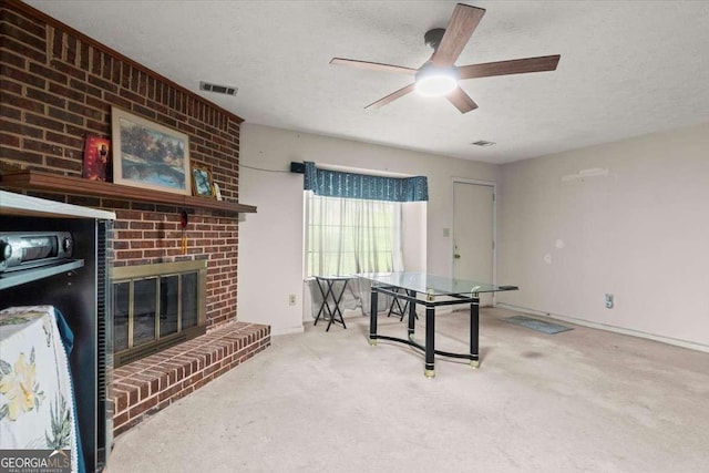 interior space with carpet flooring, ceiling fan, a textured ceiling, and a brick fireplace