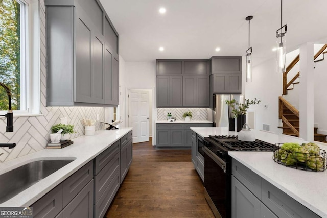 kitchen featuring stainless steel refrigerator, dark wood-type flooring, high end black range oven, pendant lighting, and gray cabinets