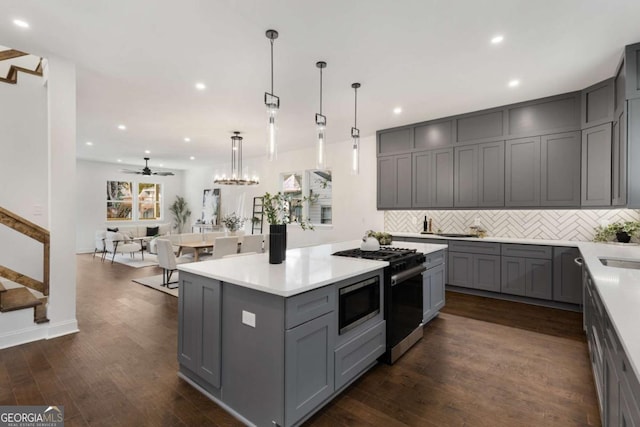 kitchen with gray cabinetry, ceiling fan, dark wood-type flooring, and stainless steel appliances