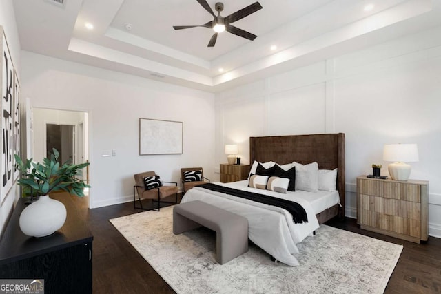 bedroom with a tray ceiling, ceiling fan, and dark hardwood / wood-style flooring